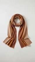 A merino wool scarf presented on a simple, illuminated with soft, with a delicate shadow underneath. The colors are warm...